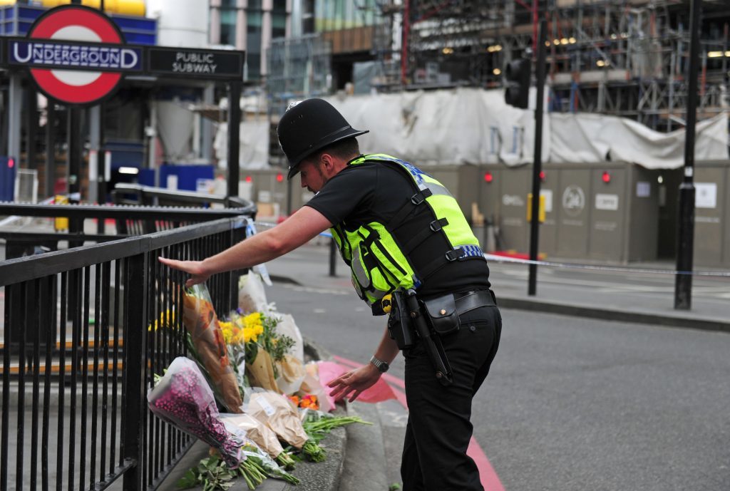 A police officer lays flowers passed to him by members of the public on the north side of London Bridge following the terrorist incident.