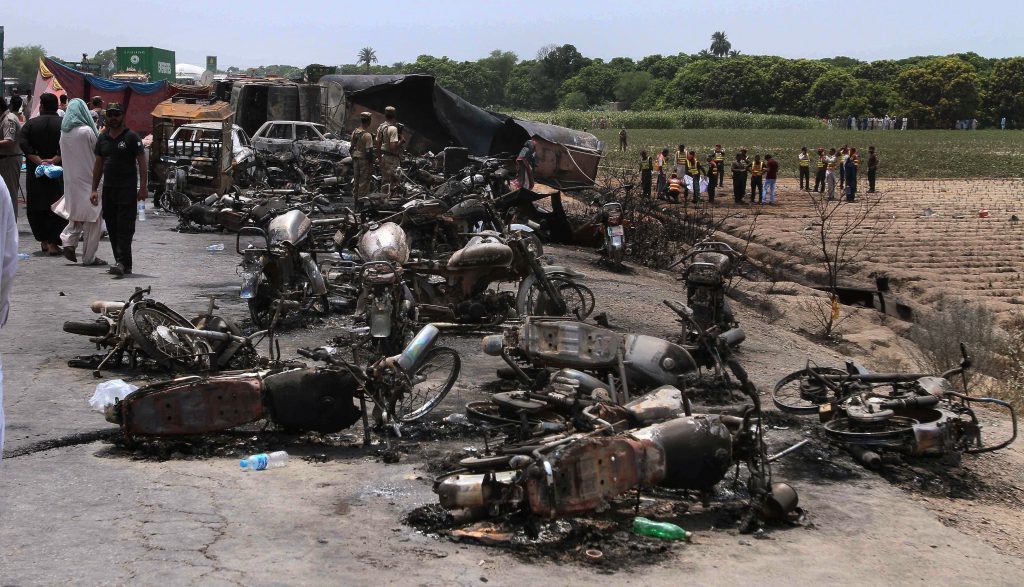 Pakistan army soldiers stands guard while rescue workers examine the site of an oil tanker explosion at a highway near Bahawalpur, Pakistan