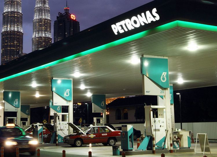 A Petroliam Nasional Bhd. (Petronas) gas station stands in front of the Petronas Twin Towers (KLCC), background center, at night in Kuala Lumpur, Malaysia. Photographer: Goh Seng Chong/Bloomberg