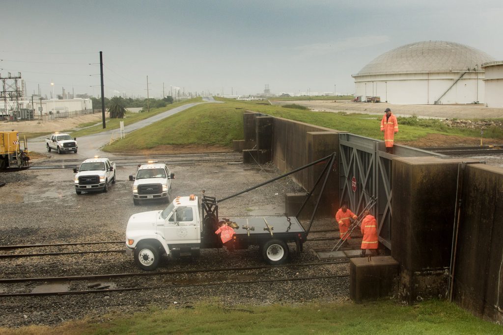 Workers secure a flood gate along the railroad tracks entering the Enterprise Products Partners LP marine terminal ahead of Hurricane Harvey in Texas City, Texas, U.S., on Friday, Aug. 25, 2017. Hurricane Harveystrengthened as it headed toward landfall in Texas, forecast to become the worst storm to strike the region in more than a decade. The price of gasolineralliedas it threatened to wreak havoc on the heart of America's energy sector. Photographer: F. Carter Smith/Bloomberg via Getty Images