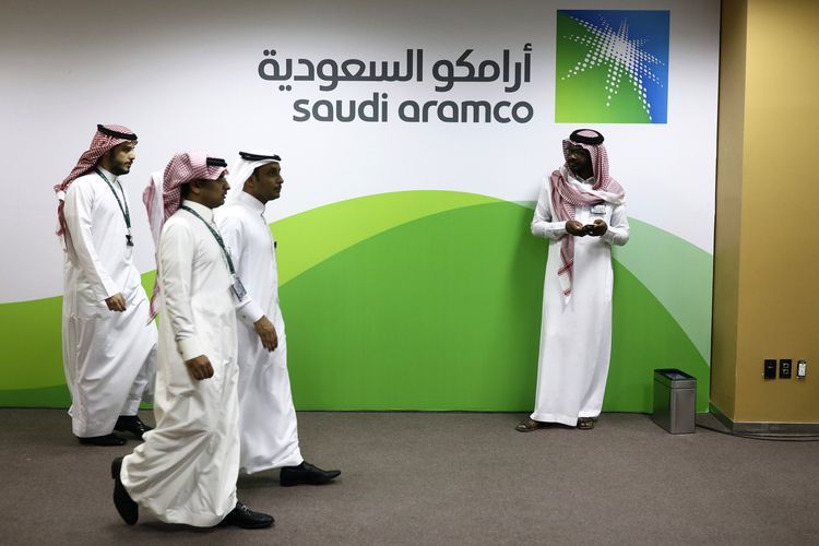 Attendees walk by a sign for the Saudi Arabian Oil Co. (Aramco) on display inside the King Abdulaziz Center for World Culture during a tour of the project in Dhahran, Saudi Arabia, on Friday, Nov. 25, 2016. When completed, the project designed for the Saudi Arabian Oil Co. (Aramco) will contain diverse cultural facilities, including an auditorium, cinema, library, exhibition hall, museum and archive. Photographer: Simon Dawson/Bloomberg