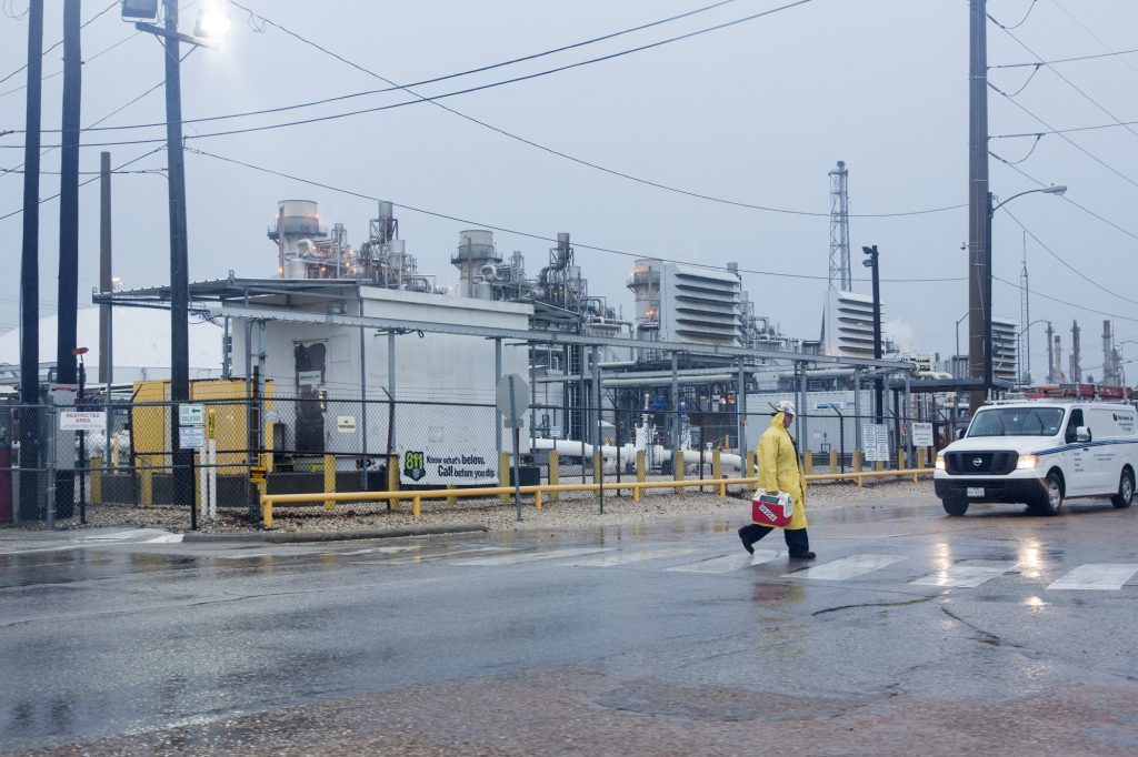 A worker wears rain gear while passing in front of the Marathon Petroleum Corp. refinery ahead of Hurricane Harvey in Texas City, Texas, U.S. Photographer: F. Carter Smith/Bloomberg