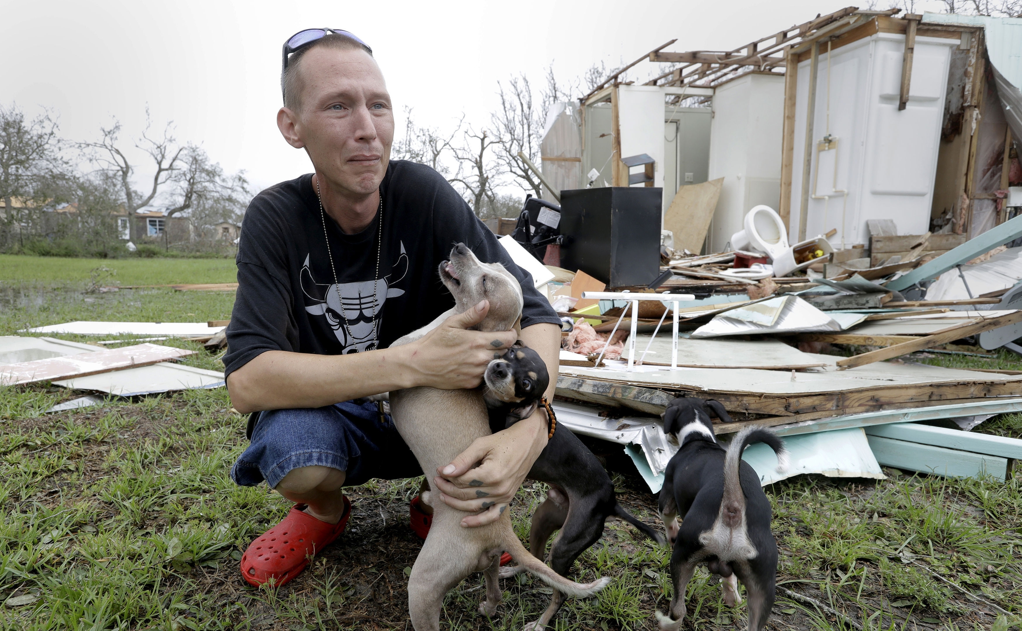Sam Speights tries to hold back tears while holding his dogs and surveying the damage to his home in the wake of Hurricane Harvey