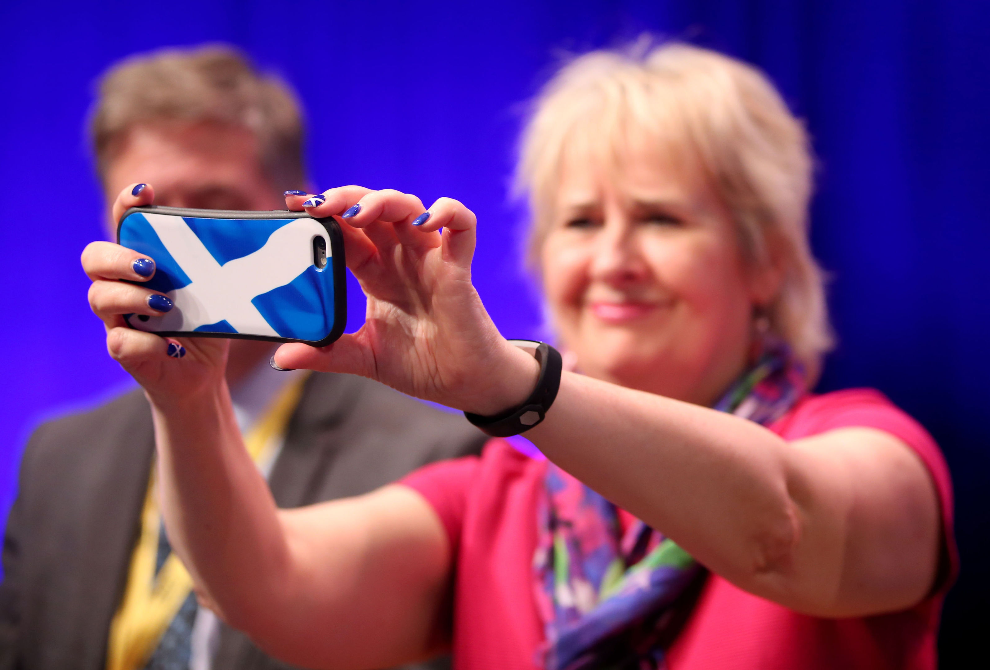 Roseanna Cunningham takes pictures on her phone as First Minister Nicola Sturgeon delivers her keynote speech at the Scottish National Party conference at the SEC Centre in Glasgow.