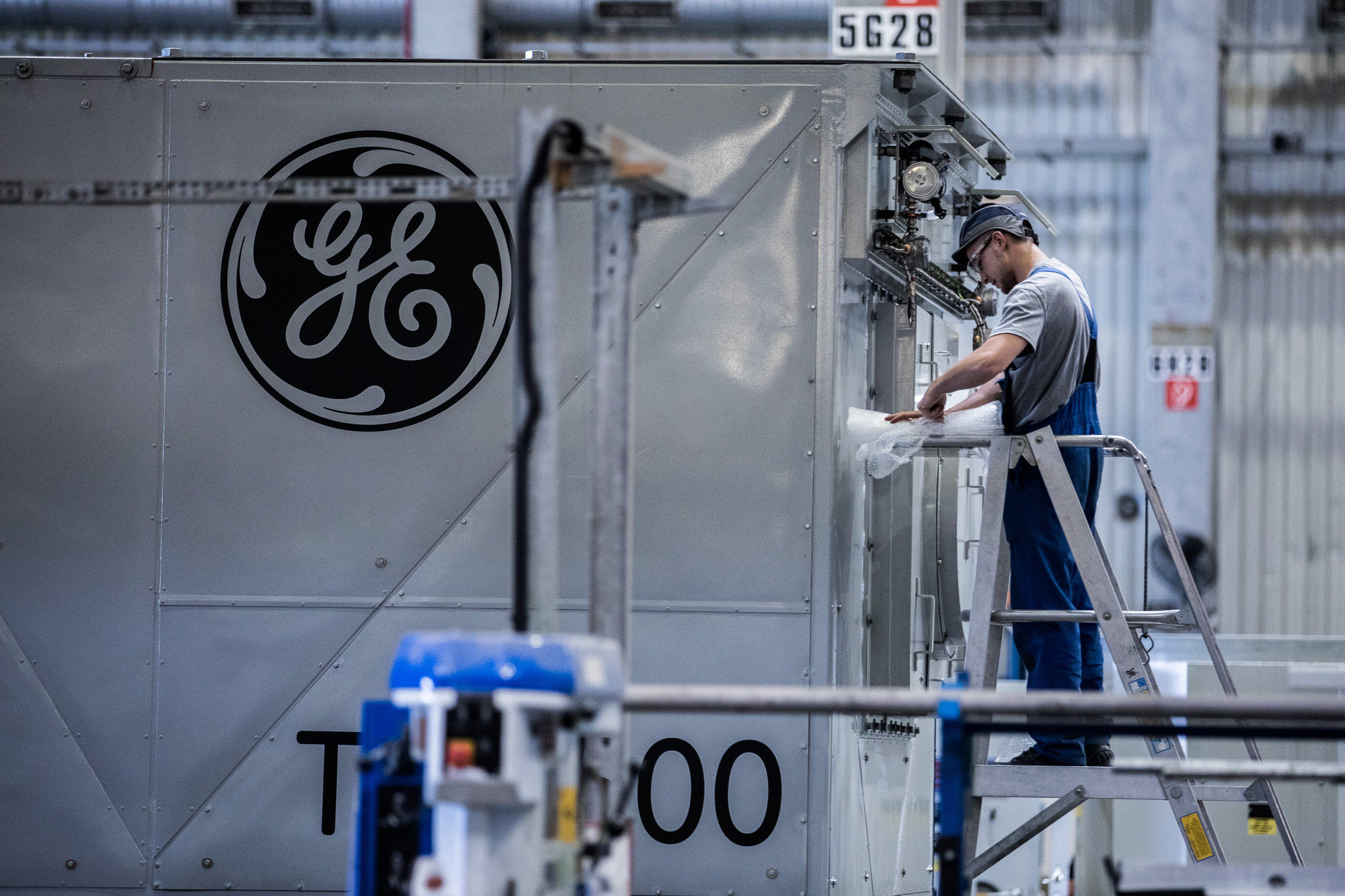 An employee unwraps turbine components inside the General Electric Co. power plant in Veresegyhaz, Hungary. Photographer: Akos Stiller/Bloomberg