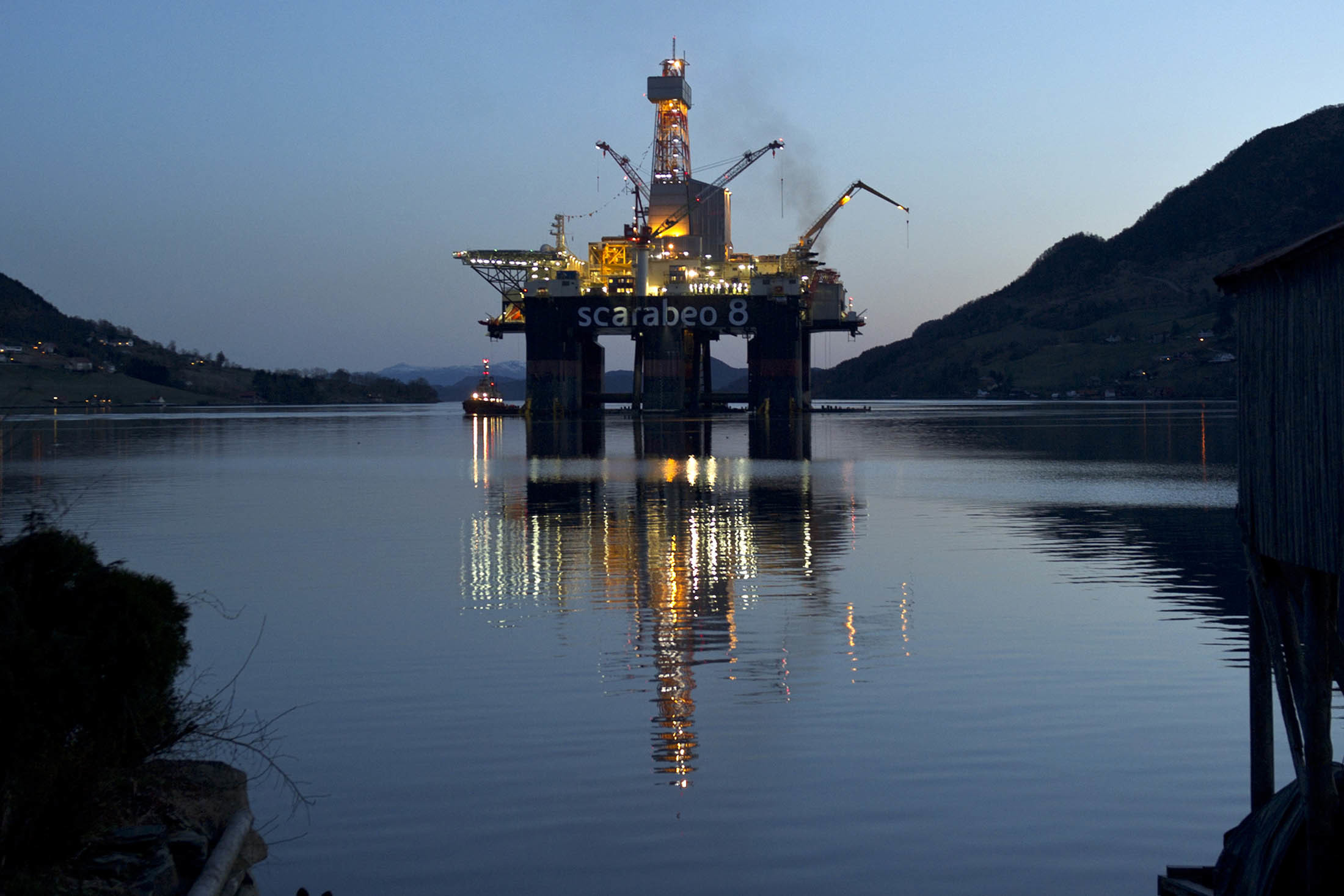 The Scarabeo 8 deepwater oil drilling rig stands illuminated at night after being re-fitted at the Westcon AS yard in Olensvag, Norway, on Tuesday, April 3, 2012.  Photographer: Kristian Helgesen/Bloomberg