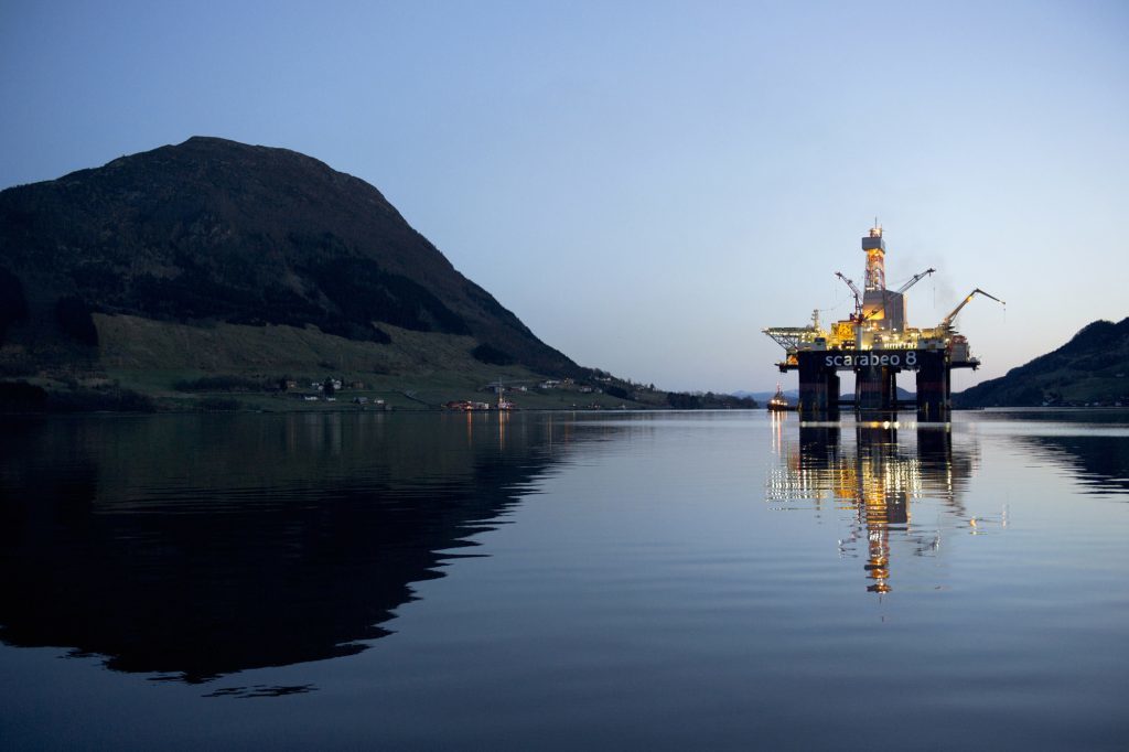 The Scarabeo 8 deepwater oil drilling rig, operated by ENI Norge AS, stands illuminated at night after being re-fitted at the Westcon AS yard in Olensvag, Norway. Photographer: Kristian Helgesen/Bloomberg