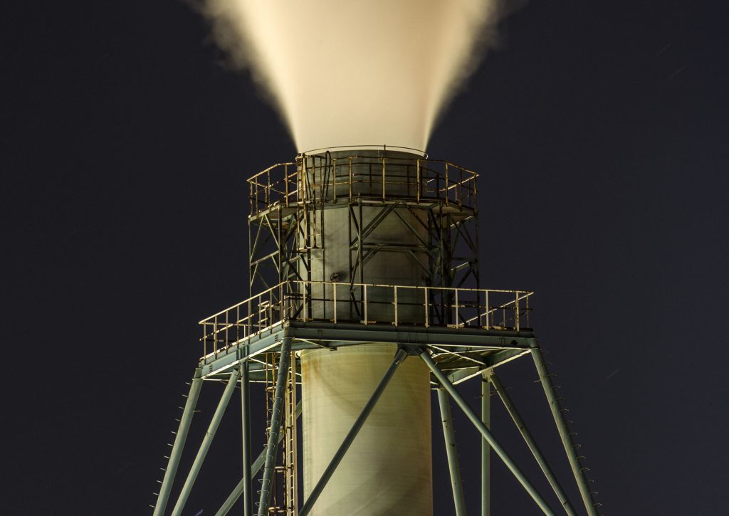 Vapor rises into the sky from a smoke stack at the JXTG Nippon Oil & Energy Corp. Muroran petrochemical plant illuminated at night in Muroran, Japan, on Friday, Oct. 27, 2017. JXTG Holdings Inc., JXTG Nippon Oil & Energy's parent company, is scheduled to announce its second-quarter earnings figures on Nov. 10. Photographer: Eiji Ohashi/Bloomberg