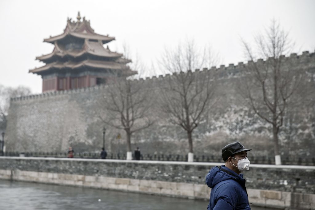 A man wearing a face mask stands next to the moat surrounding the Forbidden City in Beijing, China, on Friday, Jan. 6, 2017.  Photographer: Qilai Shen/Bloomberg