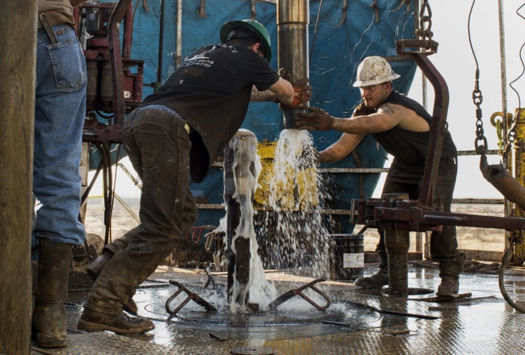 Workers connect drill bits and drill collars, used to extract natural petroleum, on Endeavor Energy Resources LP's Big Dog Drilling Rig 22 in the Permian basin outside of Midland, Texas, U.S., on Friday, Dec. 12, 2014.  Photographer: Brittany Sowacke/Bloomberg