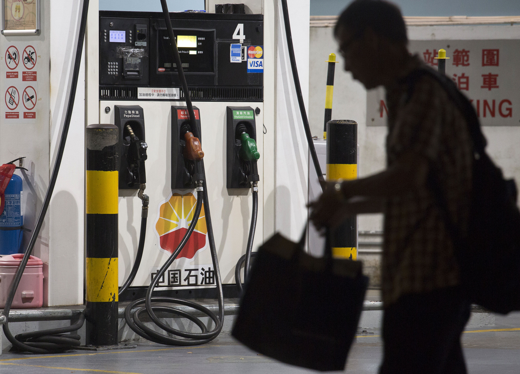 A pedestrian stands at a bus stop in front of a PetroChina Co. gas station at night in Hong Kong, China, on Monday, Aug. 21, 2017. Photographer: Vivek Prakash/Bloomberg