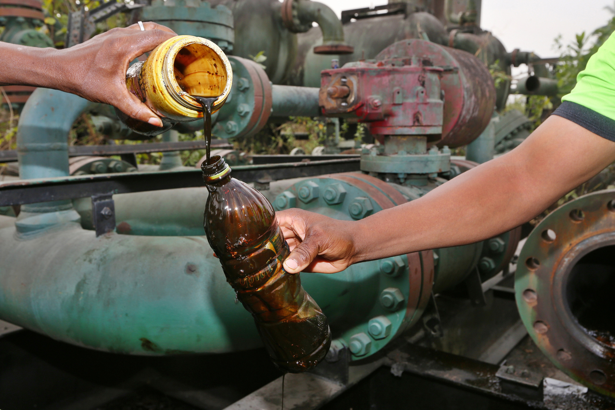 Locals pour containers of oil collected from an abandoned oil flow station operated by Royal Dutch Shell Plc in K-Dare, Nigeria. Photographer: George Osodi/Bloomberg