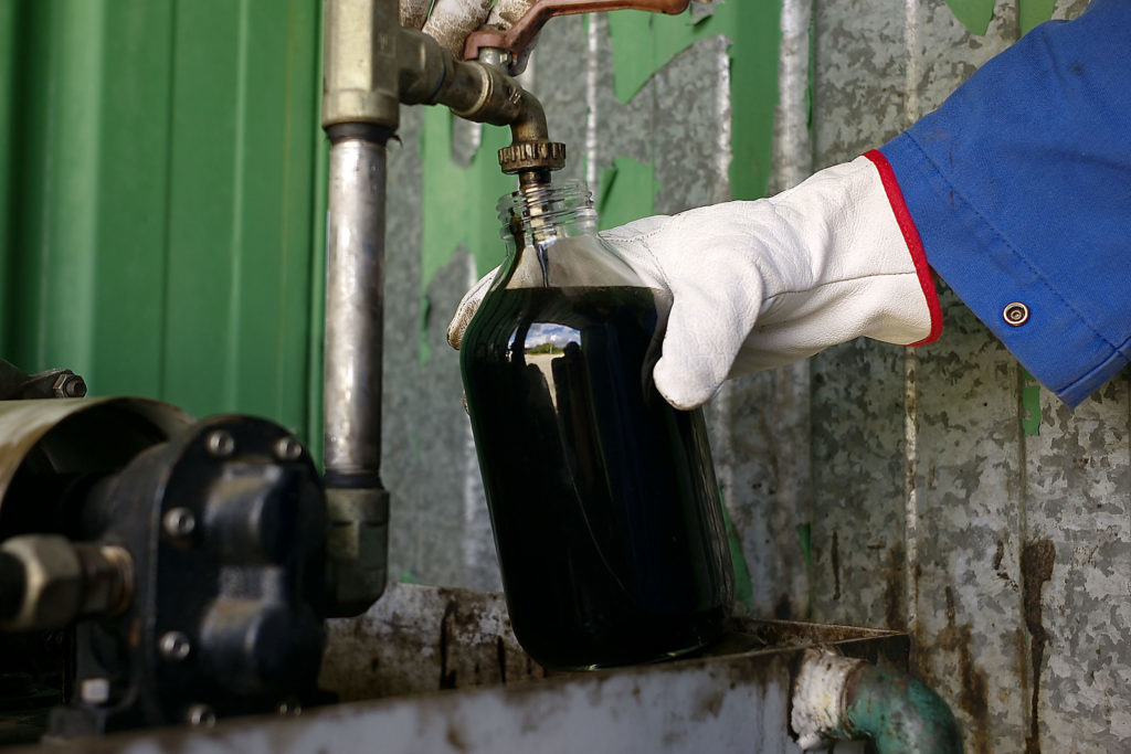 An employee takes a sample of crude oil to be sent for analysis. Photographer: Antoine Antoniol/Bloomberg