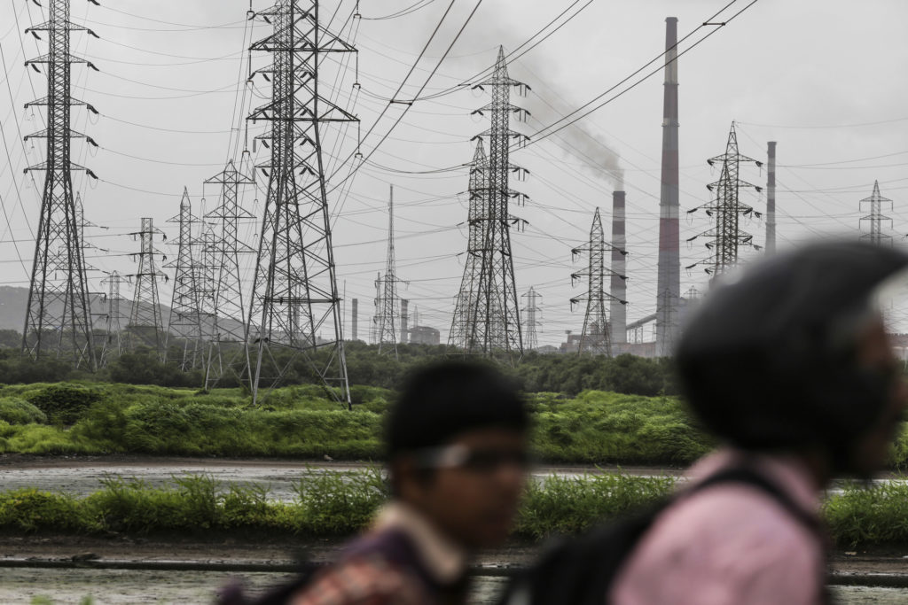 Smoke rises from a chimney as electricity pylons stand at the Tata Power Co. Trombay Thermal Power Station in Mumbai, India, on Saturday, Aug. 5, 2017. Nearly six months after his turbulent elevation to run India's biggest conglomerate, Tata Chairman Natarajan Chandrasekaran is assembling a team of dealmakers to refocus some of the groups biggest businesses, expand its financial services and consumer businesses and sell or merge dozens of smaller units, according to interviews with senior executives. Photographer: Dhiraj Singh/Bloomberg