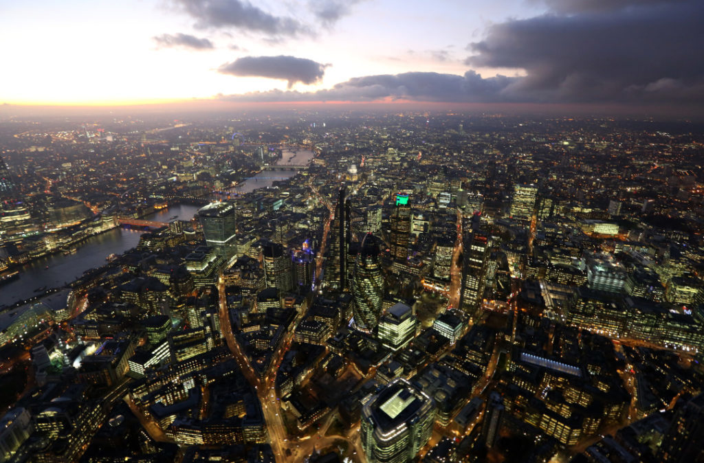 Lights illuminate the windows of skyscrapers and commercial office buildings as they stand near the banks of the River Thames in this aerial photograph taken over the City of London, in London, U.K. Photographer: Chris Ratcliffe/Bloomberg