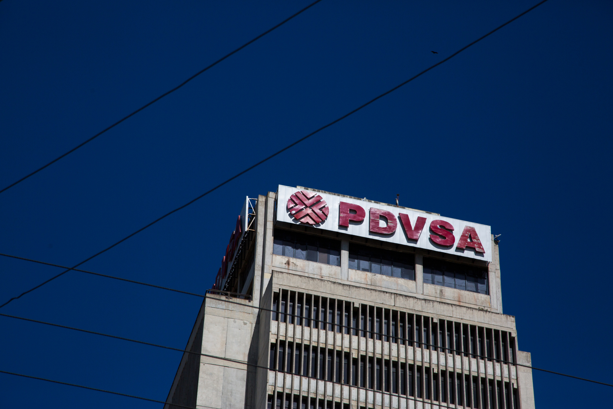 Petroleos de Venezuela SA (PDVSA) signage is displayed on a building in Puerto La Cruz, Anzoategui State, Venezuela, on Wednesday, Feb. 7, 2018. Hunger is hastening the ruin of Venezuelan's oil industry as workers grow too weak and hungry for heavy labor. Absenteeism and mass resignations mean few are left to produce the oil that keeps the tattered economy functioning. Photographer: Wil Riera/Bloomberg