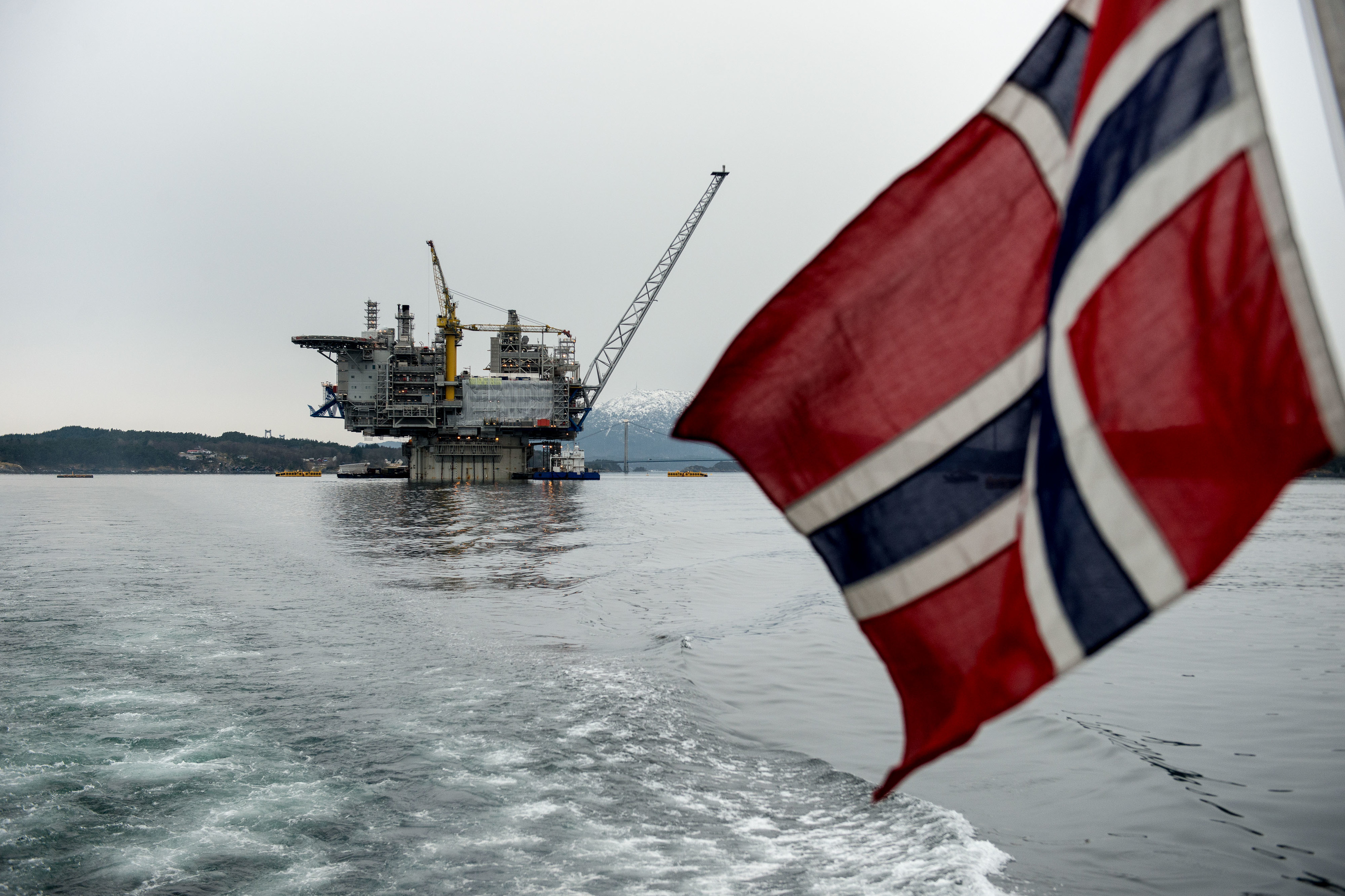 A Norwegian national flag flies from the back of a boat in view of the the Aasta Hansteen gas platform