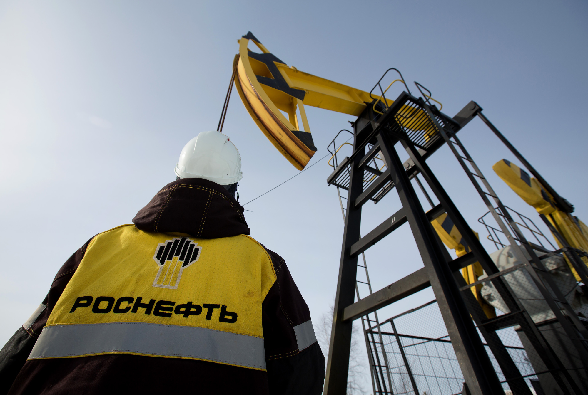 Workers inspect an oil pumping jack, also known as a 'nodding donkey' at a pumping site, operated by Rosneft PJSC, in the Samotlor oilfield near Nizhnevartovsk, Russia, on Wednesday, March 22, 2017. Russia's largest oil field, so far past its prime that it now pumps almost 20 times more water than crude, could be on the verge of gushing profits again for Rosneft PJSC. Photographer: Andrey Rudakov/Bloomberg