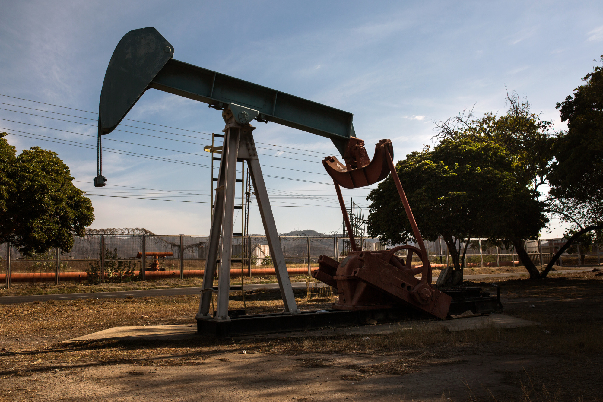An oil pump jack stands in Puerto La Cruz, Anzoategui State, Venezuela, on Wednesday, Feb. 7, 2018. Hunger is hastening the ruin of Venezuelan's oil industry as workers grow too weak and hungry for heavy labor. Absenteeism and mass resignations mean few are left to produce the oil that keeps the tattered economy functioning. Photographer: Wil Riera/Bloomberg
