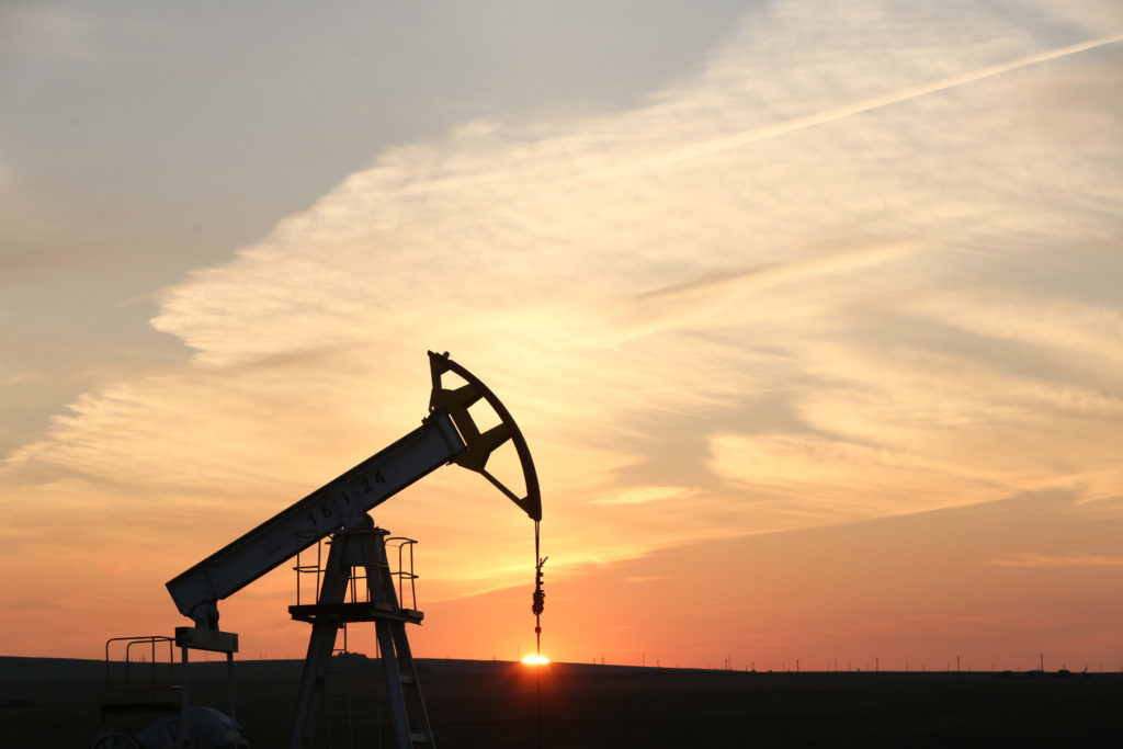 An oil pumping unit, also known as a "nodding donkey" or pumping jack, operates at sunset at a drilling site