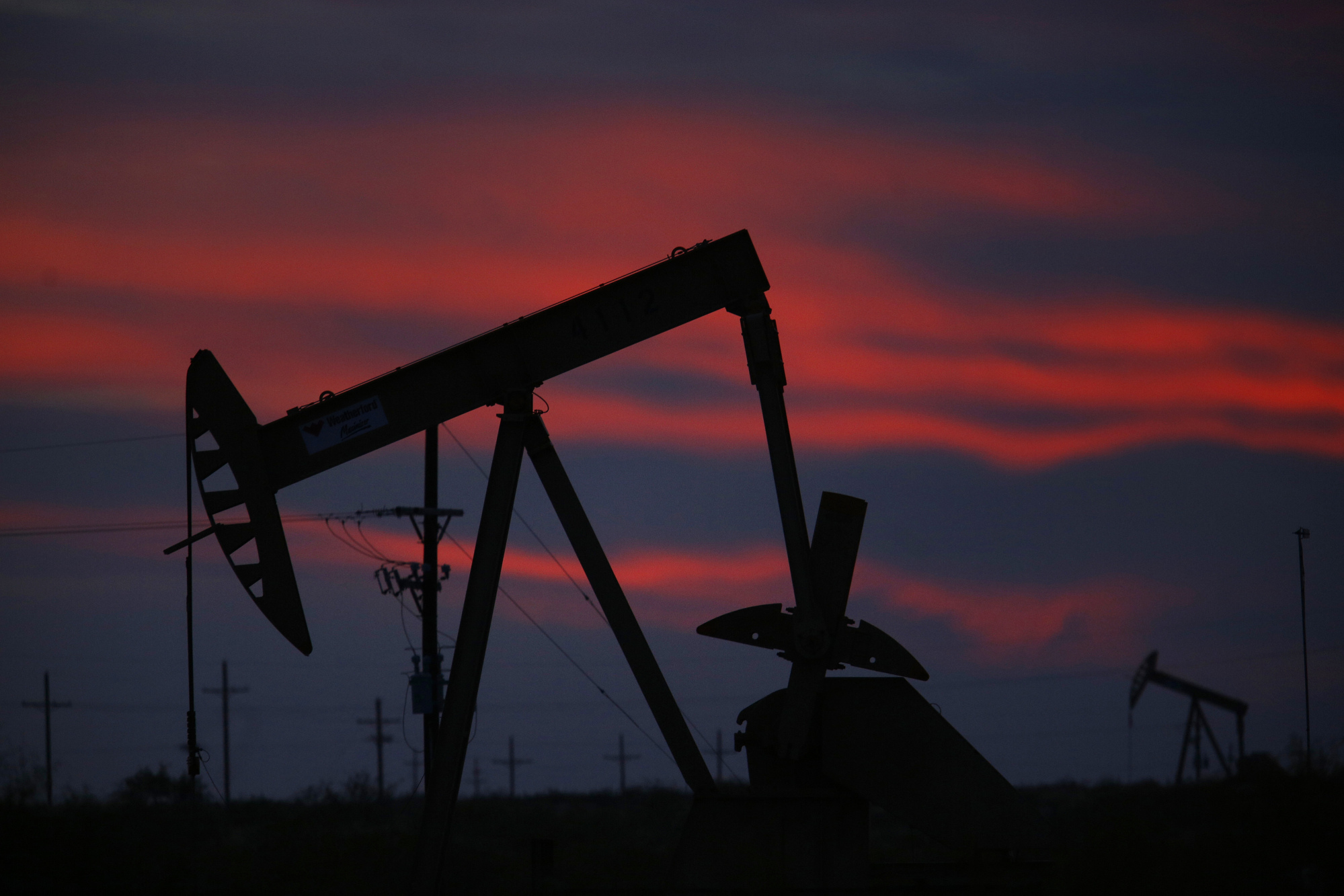 The silhouette of an electric oil pump jack is seen at dusk in the oil fields surrounding Midland, Texas, U.S., on Tuesday, Nov. 7, 2017. Photographer: Luke Sharrett/Bloomberg