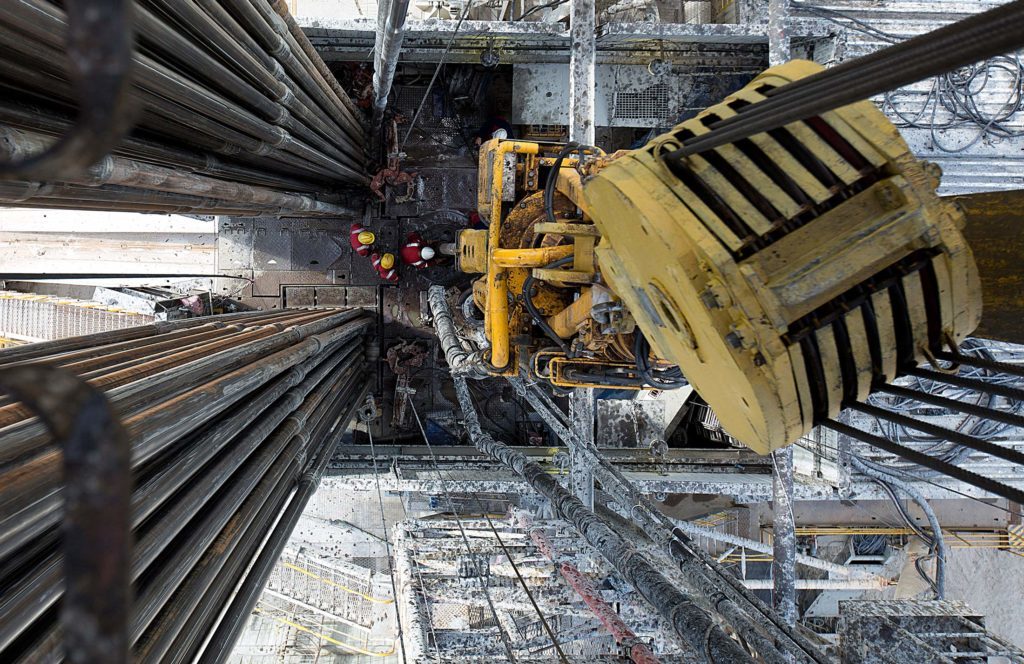 Oil workers operate drill sections while working on the drilling floor beneath the travelling block, right, on a derrick operated by Salym Petroleum in Salym, Khanty-Mansi autonomous region, Russia, on Tuesday, July 2, 2013. Oil extended losses below $60 a barrel amid speculation that OPEC's biggest members will defend market share against U.S. shale producers. Photographer: Bloomberg/Bloomberg