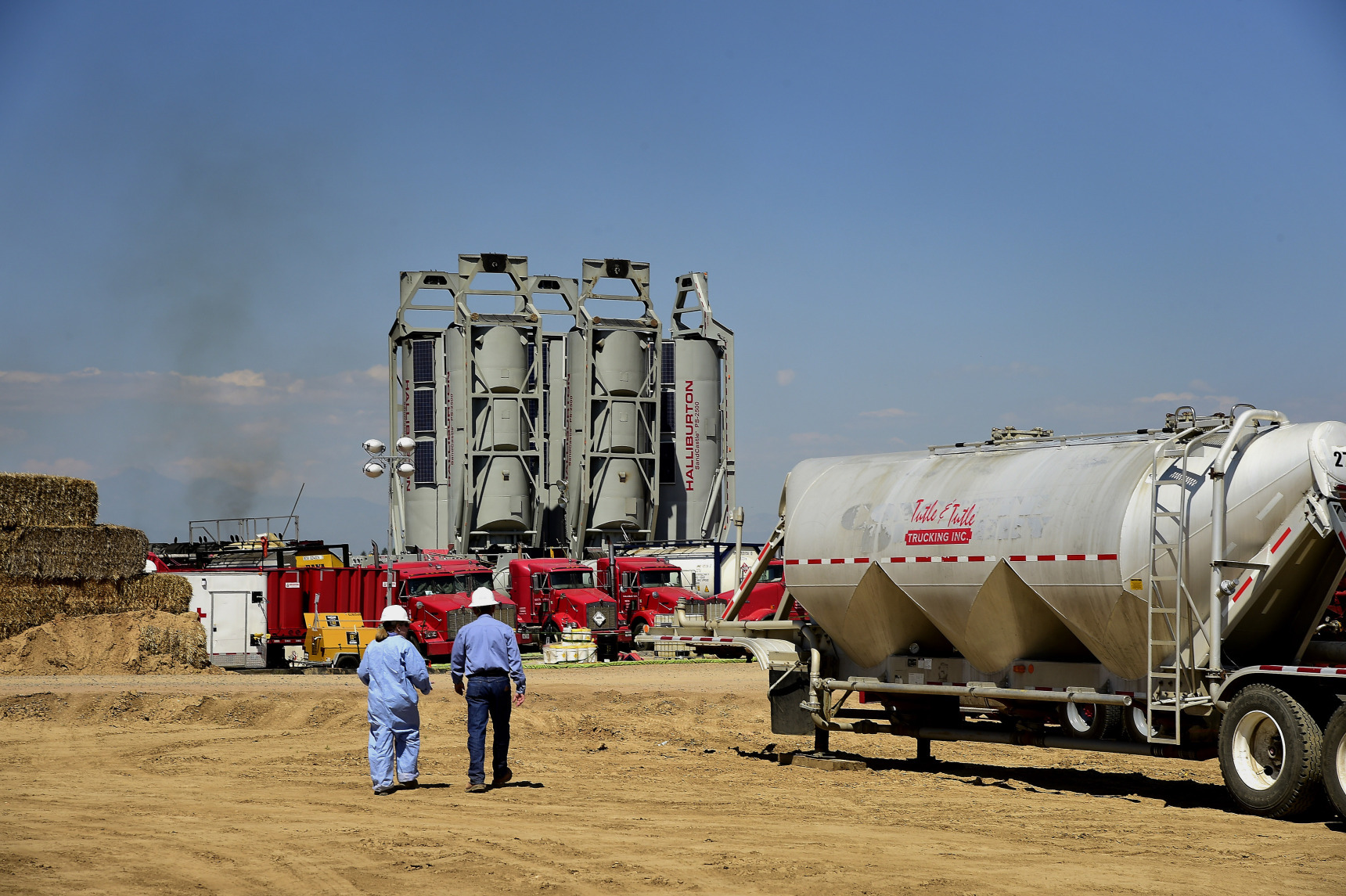 Workers walk towards Halliburton Co. "sand castles" at an Anadarko Petroleum Corp. hydraulic fracturing (fracking) site north of Dacono, Colorado, U.S. Photographer: Jamie Schwaberow/Bloomberg