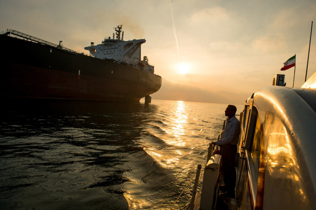 A support vessel flying an Iranian national flag sails alongside the oil tanker 'Devon' as it prepares to transport crude oil to export markets in Bandar Abbas, Iran, on Friday, March 23, 2018. Geopolitical risk is creeping back into the crude oil market. Photographer: Ali Mohammadi/Bloomberg