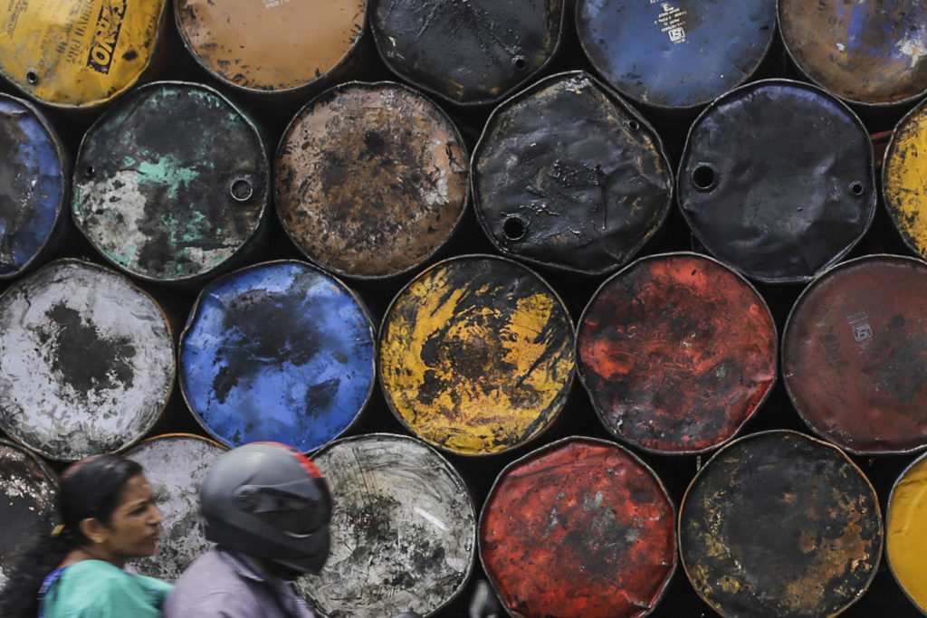 India's ONGC needs to pump more oil: a motorcyclist drives past empty stacked oil drums in Cochin, India, on Friday, May 29, 2015.  Photographer: Dhiraj Singh/Bloomberg