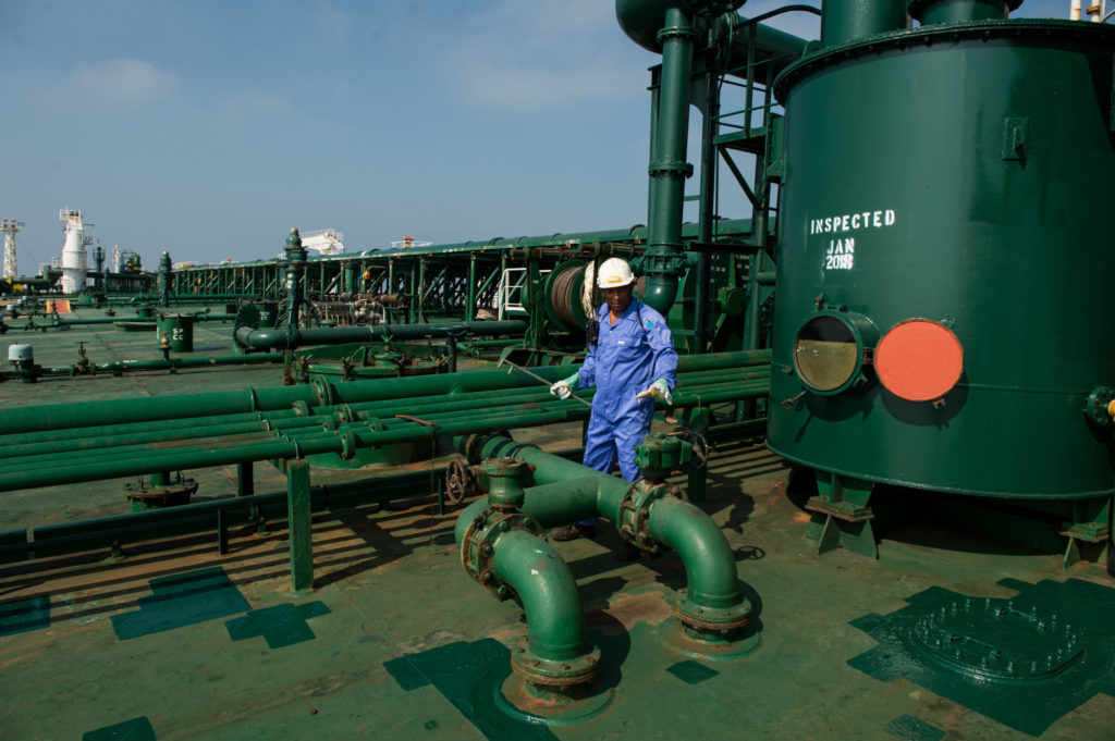 A crew man works on the deck of oil tanker 'Devon' as it prepares to transport crude oil from Kharq Island to India in Bandar Abbas, Iran, on Friday, March 23, 2018. Geopolitical risk is creeping back into the crude oil market. Photographer: Ali Mohammadi/Bloomberg