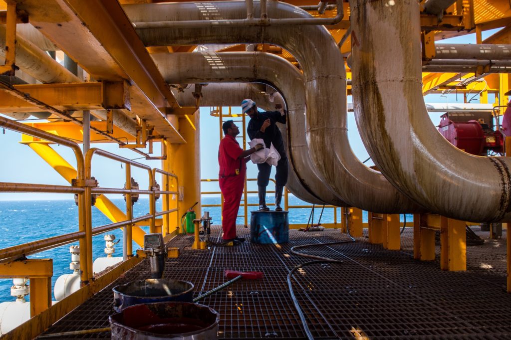 Workers clean oil leaks from pipes aboard an offshore oil platform in the Persian Gulf's Salman Oil Field, operated by the National Iranian Offshore Oil Co., near Lavan island, Iran, on Thursday, Jan. 5. 2017.  Photographer: Ali Mohammadi/Bloomberg