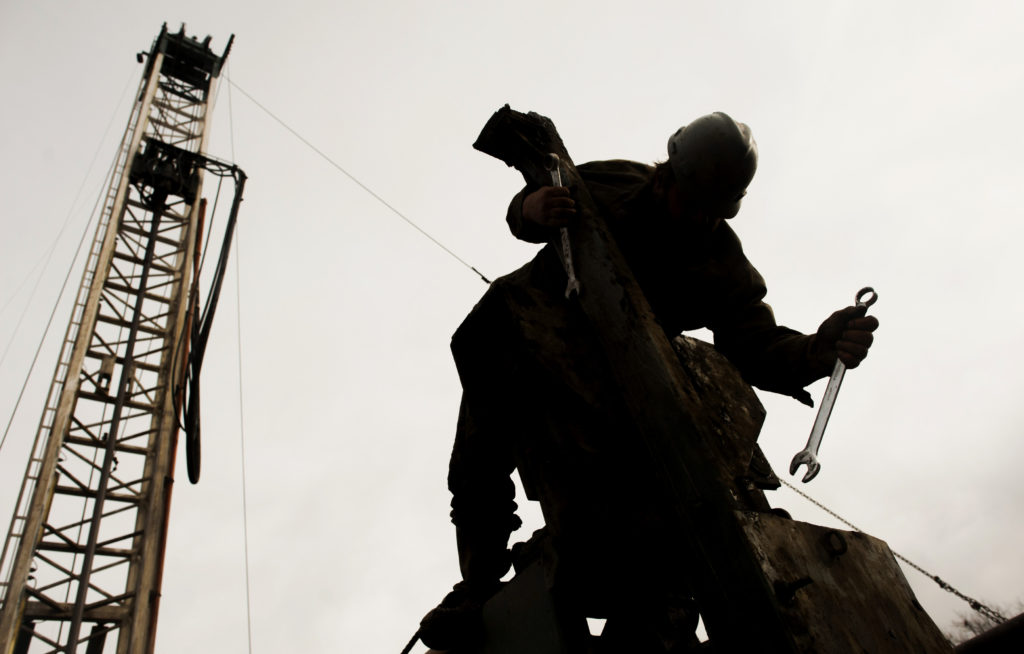 The silhouette of a rig hand is seen repairing the boom arm. Photographer: Ty Wright/Bloomberg