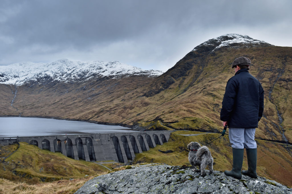 A boy and his dog view Cruachan hydro electric power station in Argyll.