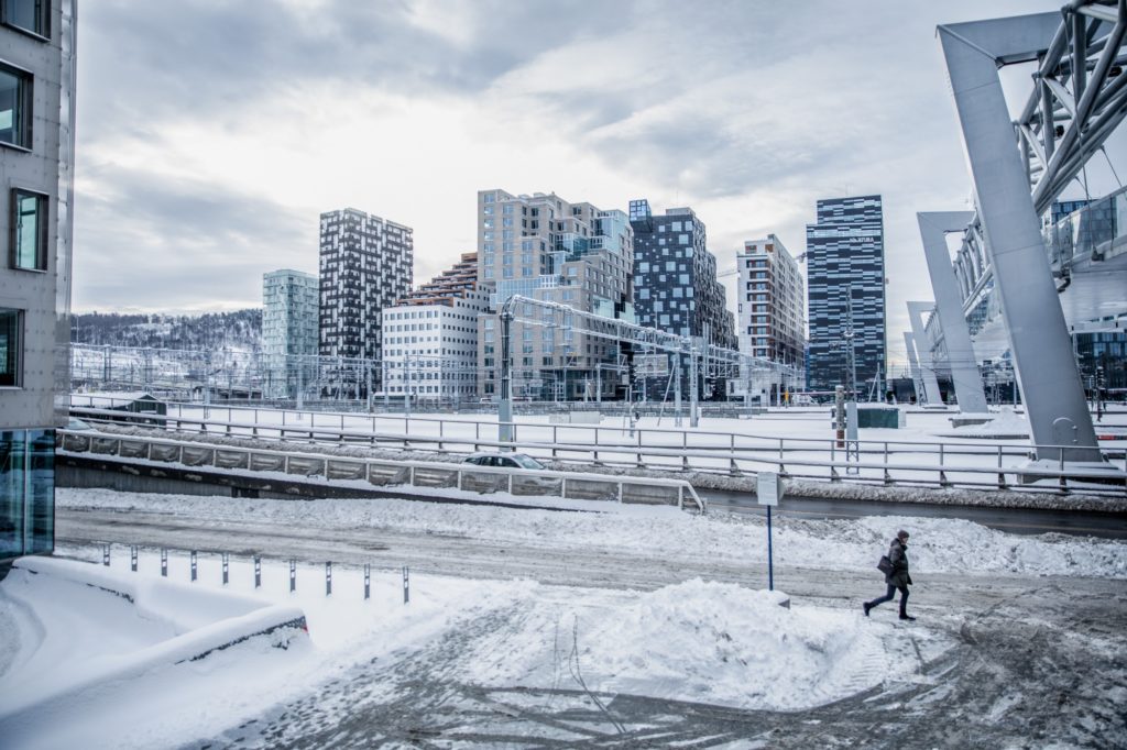 A pedestrian walks past buildings in the Barcode neighborhood of Oslo. Photographer: Odin Jaeger/Bloomberg