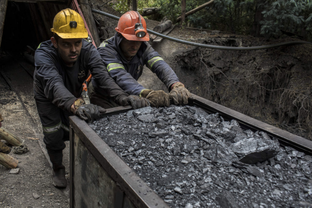 Miners push a wagon of coal outside a mine in Cucunuba, Cundinamarca Department, Colombia, on Friday, July 28, 2017.