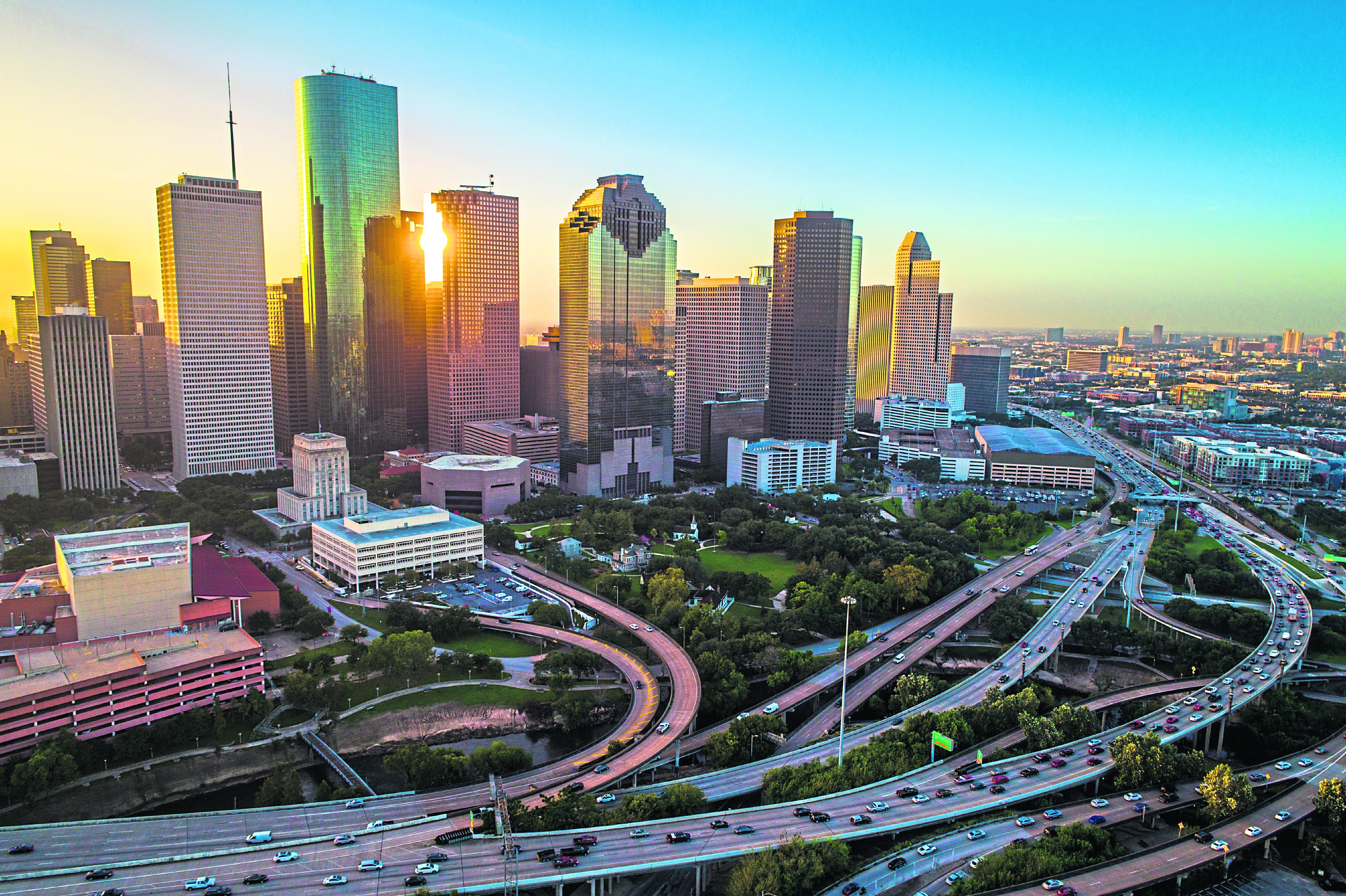 Houston - istock - Houston Texas aerial drone sunrise view cityscape skyline colorful morning downtown - highways , traffic , office buildings and high rises Home sales and modern architecture of the Houston real estate market - new modern homes for sale on Houston Texas on a sunny day