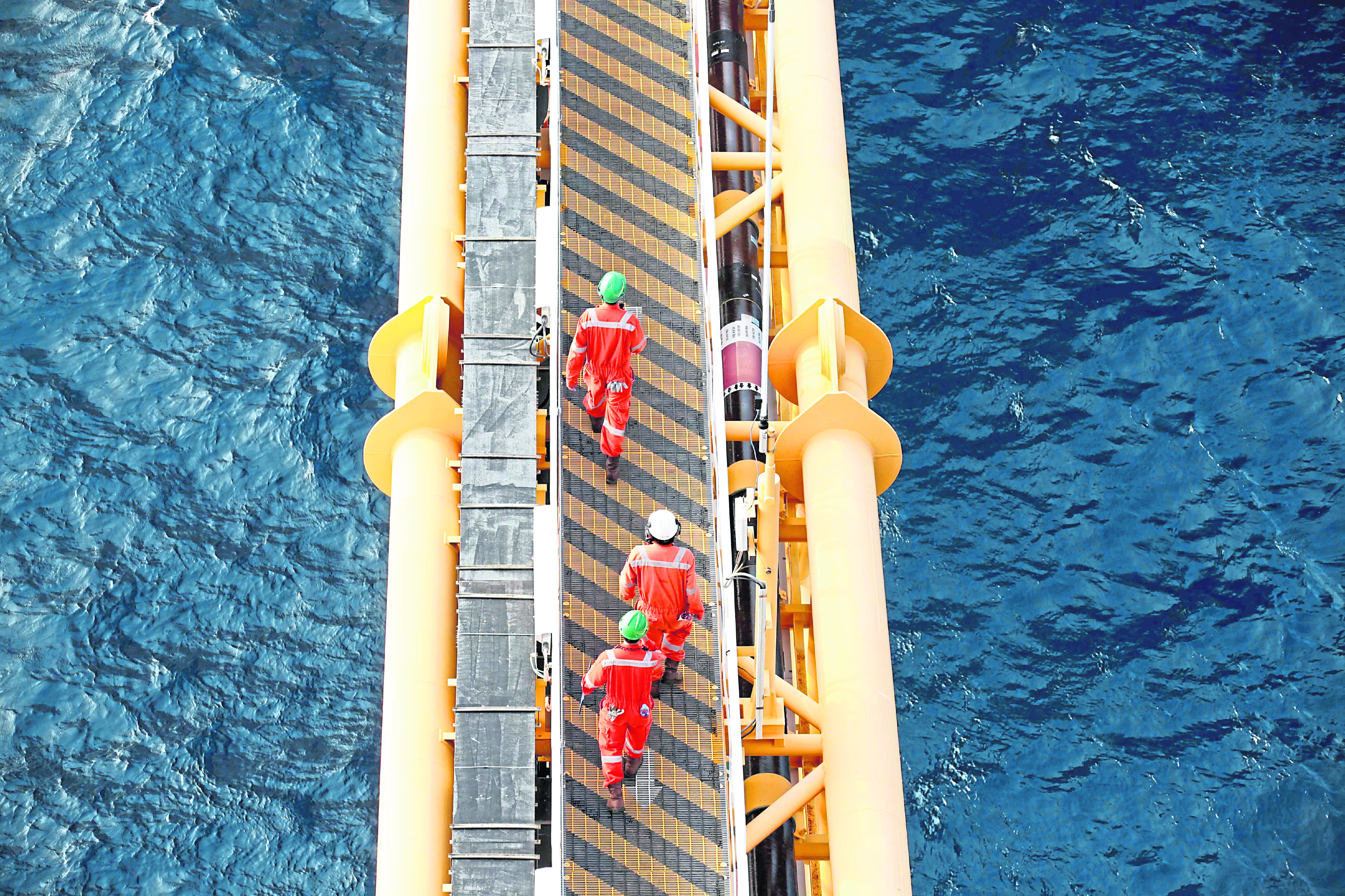 Workers cross a platform bridge
BLACK GOLD