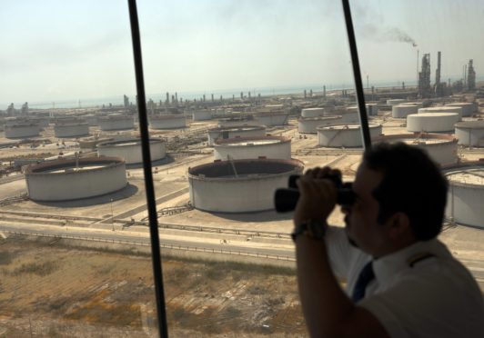 An employee uses binoculars to look out towards the Arabian Sea in the Port Control Center at Saudi Aramco's Ras Tanura oil refinery and terminal in Ras Tanura, Saudi Arabia, on Monday, Oct. 1, 2018. Photographer: Simon Dawson/Bloomberg