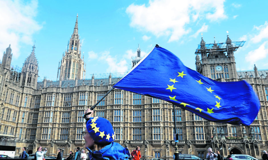 An anti Brexit campaigner shows her support for Europe waving a European Union flag outside Parliament in London, Monday, March 25, 2019.  British Prime Minister Theresa May is under intense pressure Monday to win support for her Brexit deal to split from Europe. (AP Photo/Kirsty Wigglesworth)