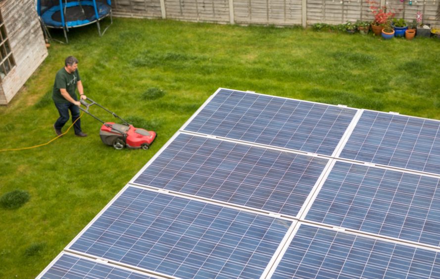 Hill mows his lawn in view of his solar panels.  Photographer: Chris Ratcliffe/Bloomberg