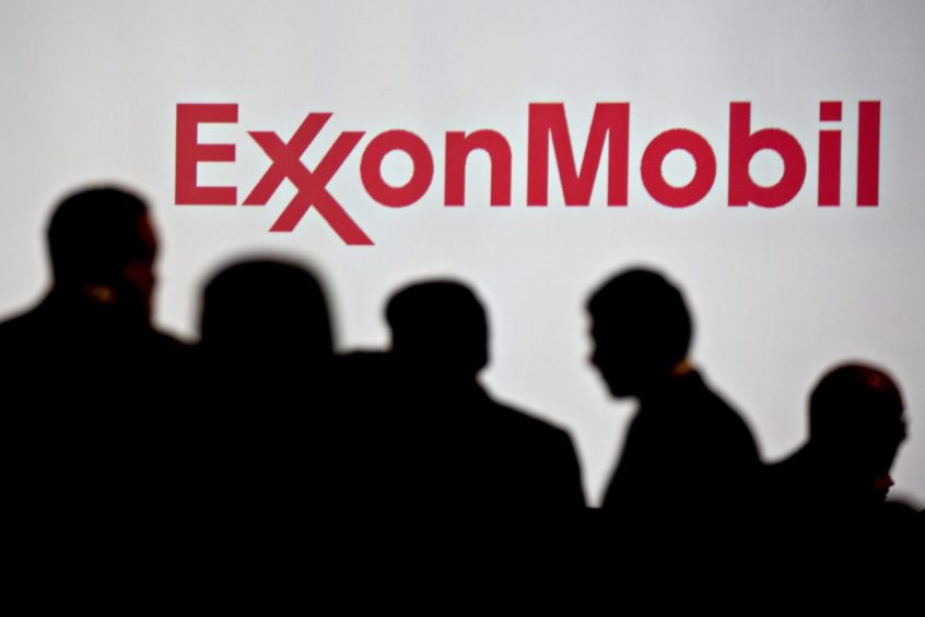 Attendees stand near Exxon Mobil Corp. signage during the World Gas Conference in Washington, D.C.,