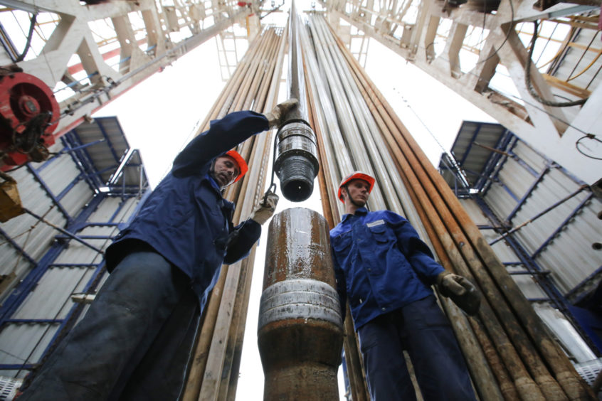 Workers secure drilling pipe sections on an oil drilling tower operated by Tatneft OAO near Almetyevsk, Russia, on Friday, July 31, 2015. Photographer: Andrey Rudakov