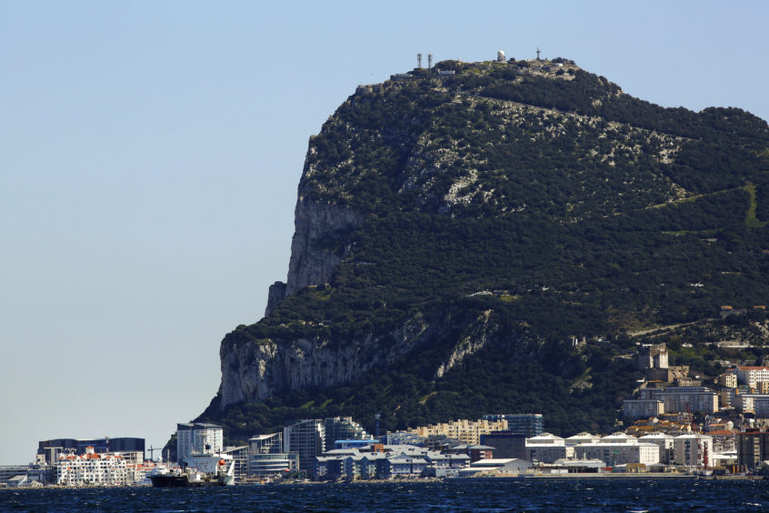 Commercial and residential buildings stand along the waterline at the base of the rock of Gibraltar in Gibraltar, U.K., on Sunday, March 6, 2016.  Photographer: Luke MacGregor/Bloomberg
