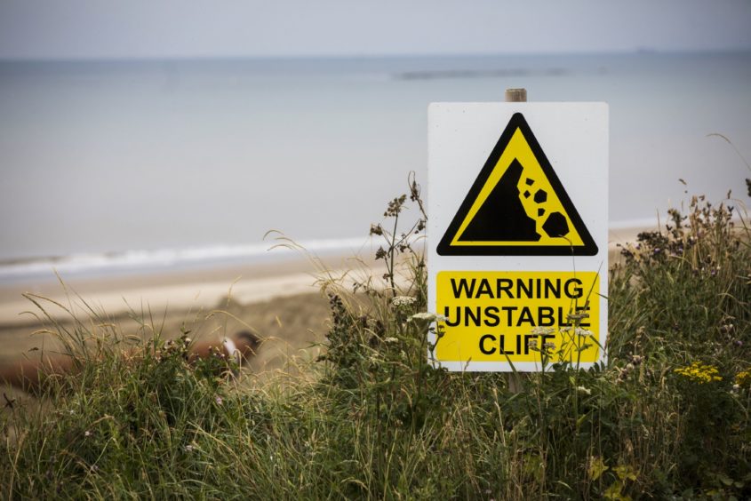 A sign stands at the cliff edge during an operation by Royal HaskoningDHV to protect against erosion of the cliffs bordering the Bacton Gas Terminal