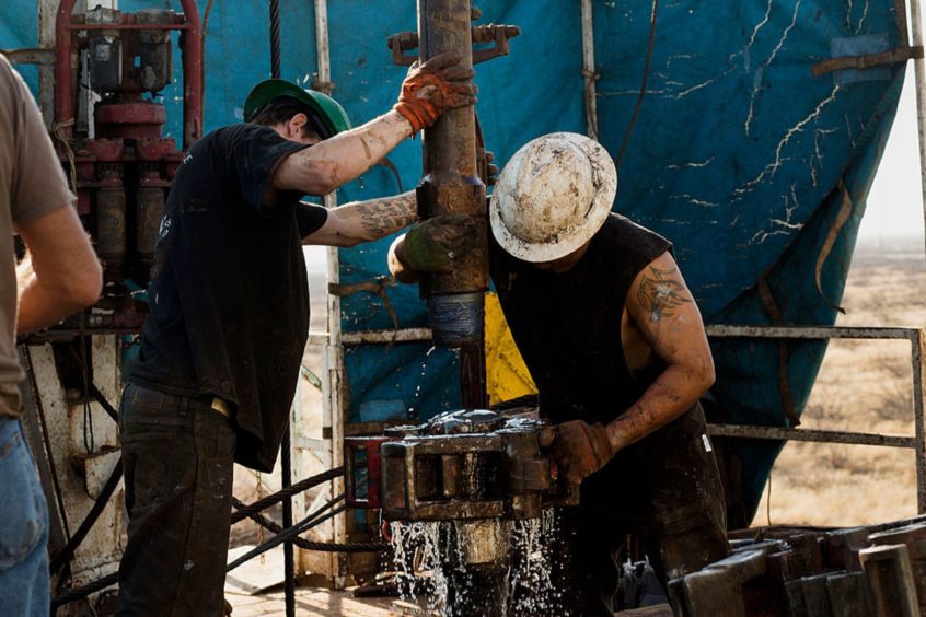 Workers on Big Dog Drilling Rig 22, owned by Endeavor Energy Resources, L.P., on the outskirts of Midland, Texas, connect drill bits and drill collars used to extract natural petroleum on Friday, December 12, 2014. (Brittany Sowacke/Bloomberg)