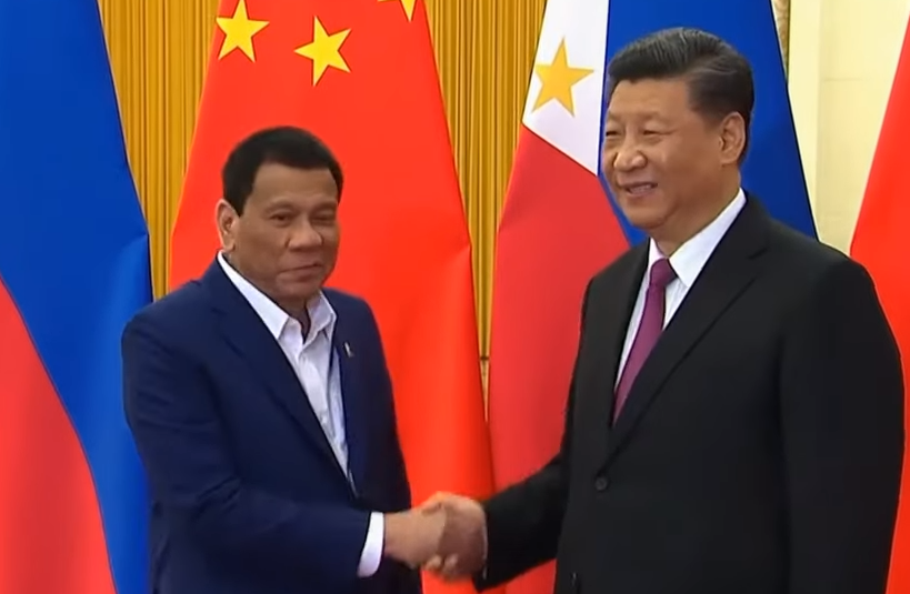 The presidents of China (right) and the Philippines shake hands.