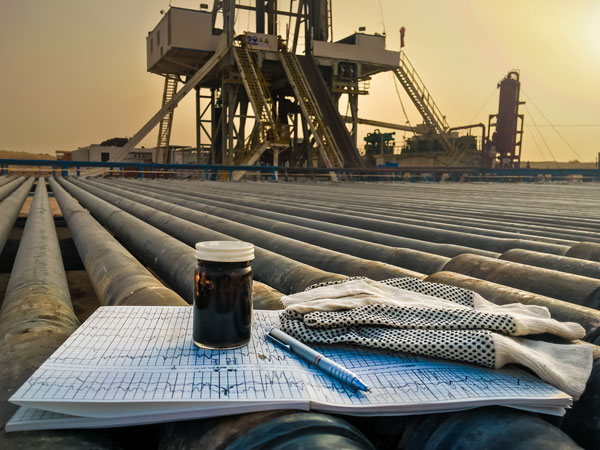 A rig in the background, in the foreground a book with a jar and oil inside