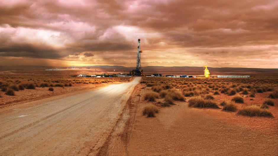 Drilling rig at end of a dusty road, with orange sky