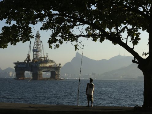 A man fishes in Guanabara Bay while an oil drilling platform floats in the background near Niteroi, Brazil, on Monday, April 20, 2015. Petroleo Brasileiro SA (Petrobras), the state-controlled oil producer at the center of an ever-widening corruption investigation, plans to release its audited third-quarter and 2014 results after markets close on April 22, 2015, ending a five-month wait for investors. Photographer: Dado Galdieri/Bloomberg