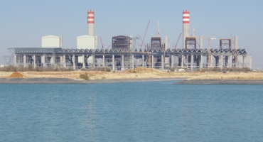 Blue sea in foreground, with cooling towers behind